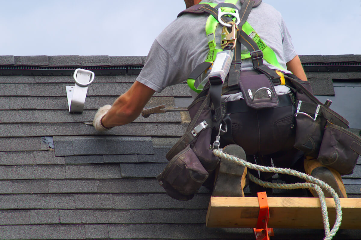 A roofer in safety harness.